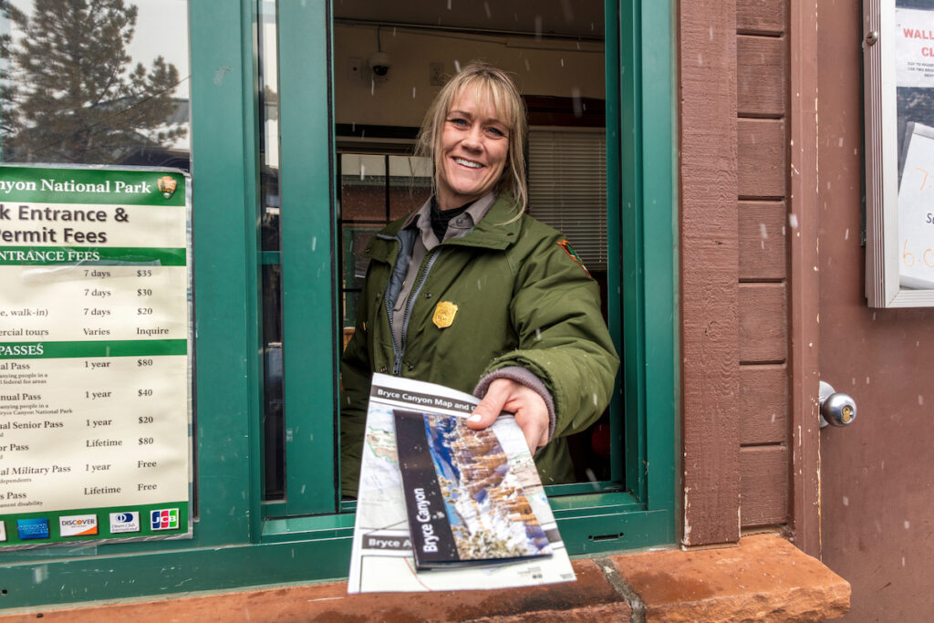 Female blond National Park Ranger hands out brochure through window at Bryce National Park, Utah.