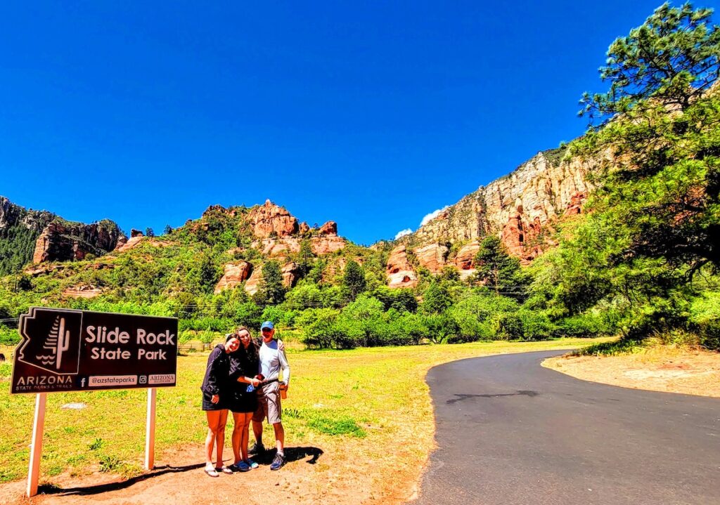 Views from the entrance with guest standing next to the Slide Rock State Park sign.